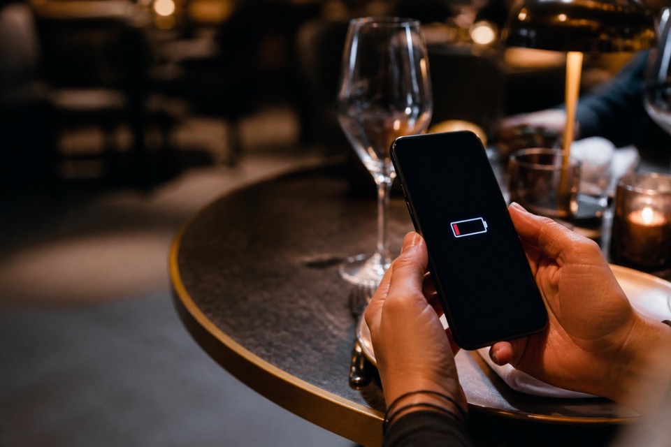 Guest checking a low phone battery while seated at a restaurant table